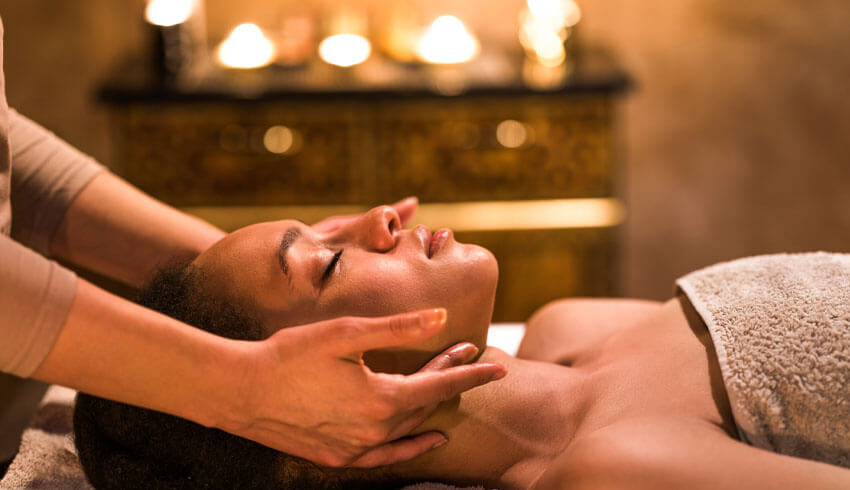 A woman lying on a spa treatment table with soft lighting in the background